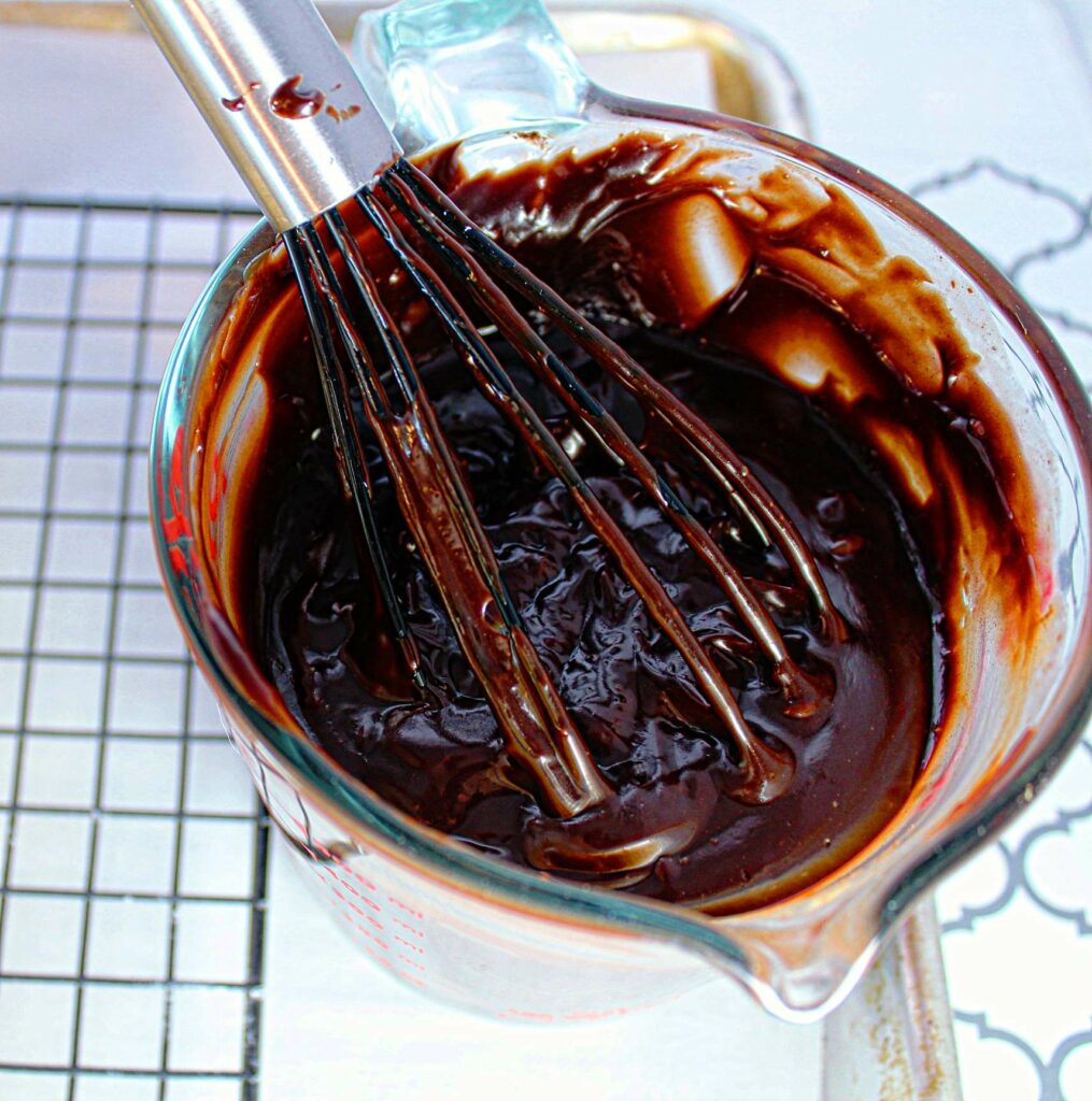 brownie batter in a large measuring cup with a whisk